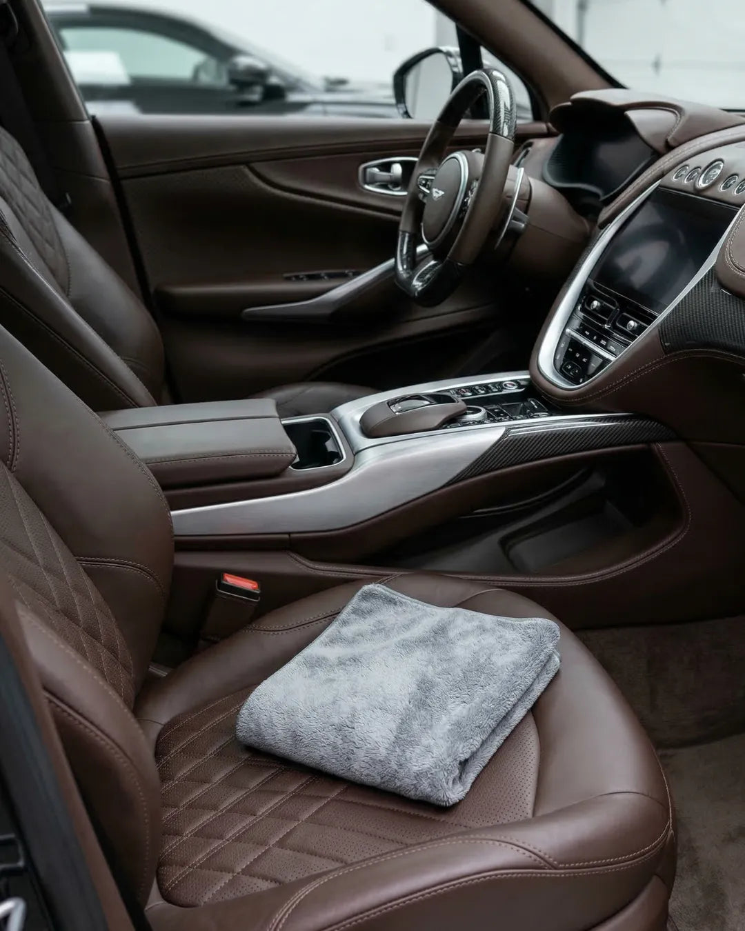 Spotless luxury car interior with a microfiber cloth on a leather seat.
