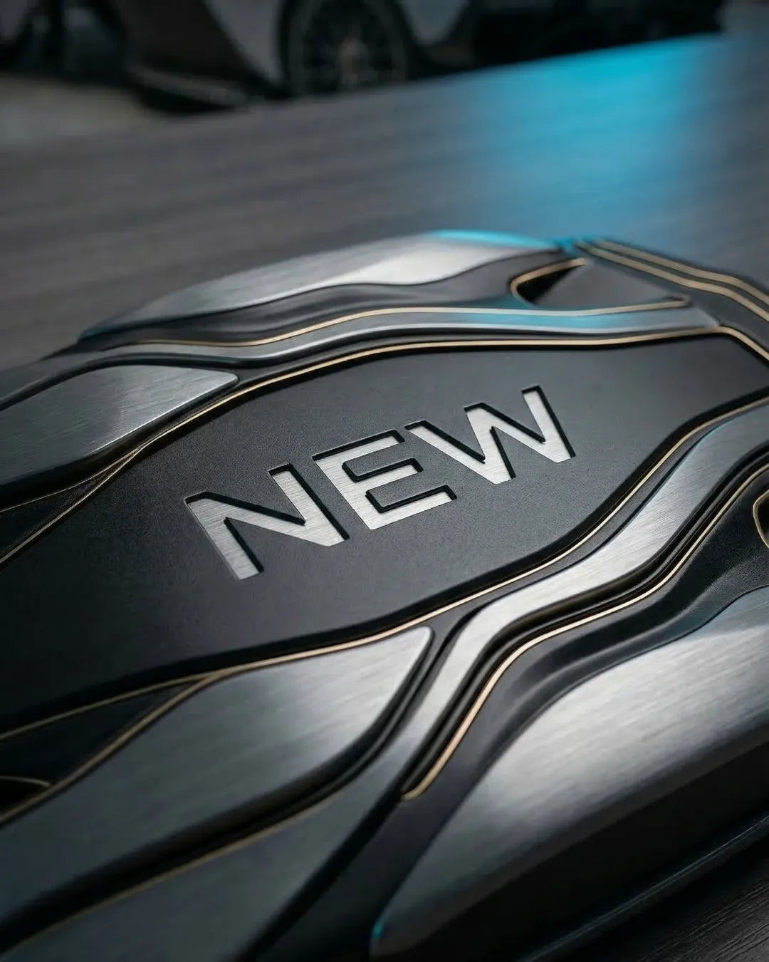 Close-up of a premium matte black car amplifier with the word 'NEW' debossed into the metallic casing.
